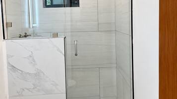 Ein modernes Badezimmer mit einer gläsernen Duschkabine, einer Toilette und einem Waschbecken.