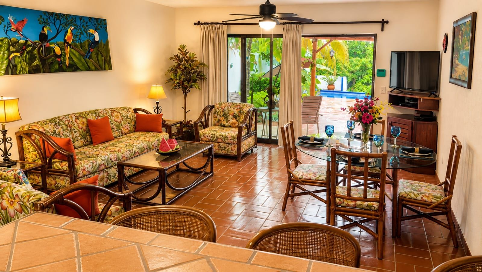 A living room with a sofa, chairs, a coffee table, a TV, and a dining area with a table and chairs.