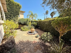 A garden with a central decorative feature surrounded by various plants and a gravel path. - Beautiful 2-bedroom house with AC in charming Santa Barbara (Santa Barbara)