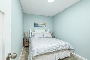 A bedroom with a bed, bedside tables, and a wall-mounted picture.