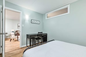 A bedroom with a bed, a desk with chairs, a door leading to another room, and a wall-mounted picture. - K's Condominium - Minutes to Ski, Trails, Shops, Beach (Collingwood)