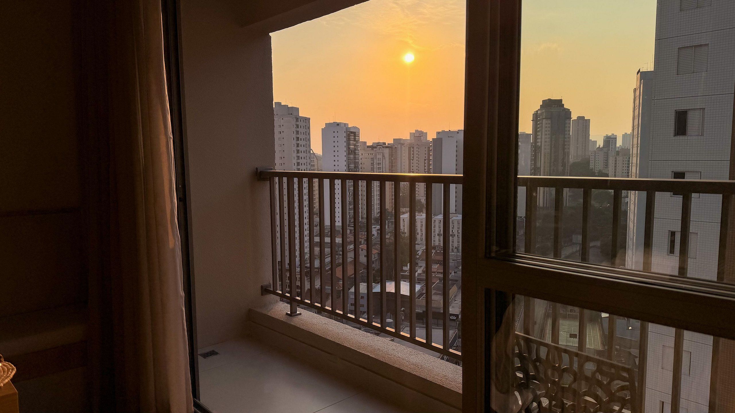 Un balcón con vista a la ciudad durante el atardecer.