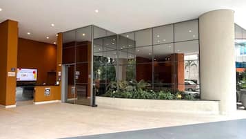 A modern building entrance with glass doors, a reception desk, and a sign indicating a Valet service.