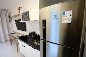 Una cocina moderna con un refrigerador de acero inoxidable, una cafetera y un televisor de pantalla plana montado en la pared.