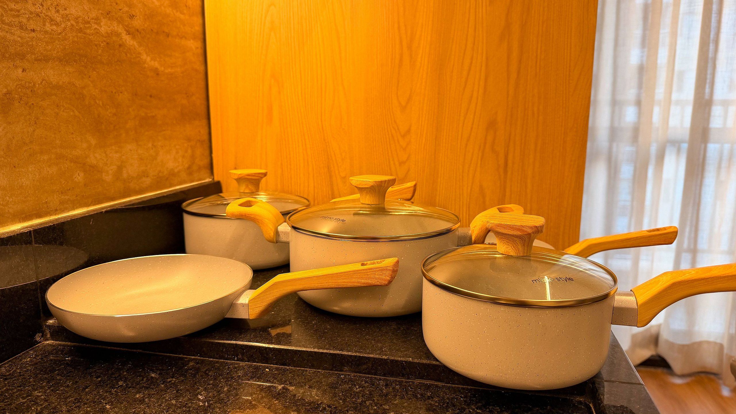 Una encimera de cocina con varias ollas y sartenes, algunas con asas y tapas de madera.