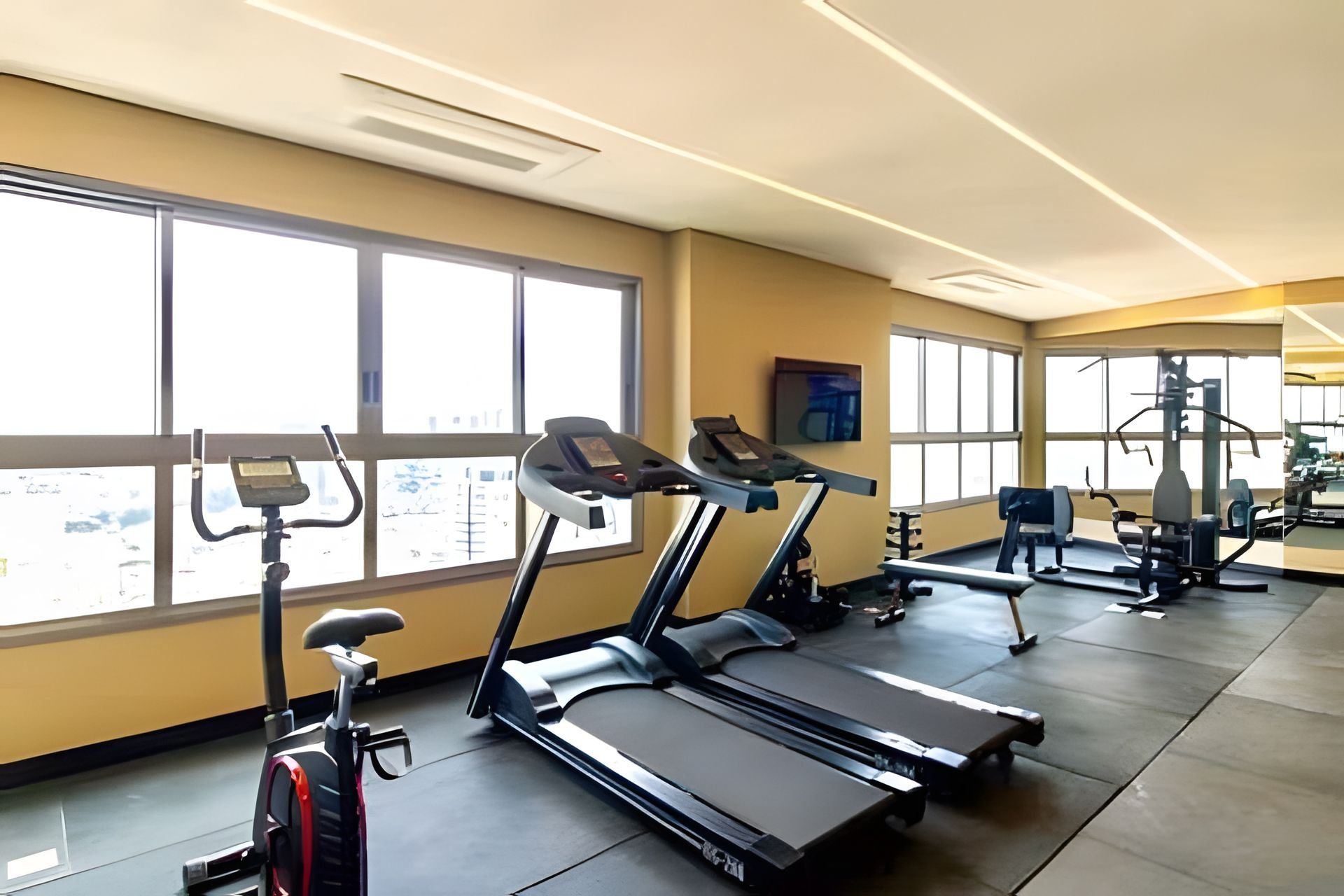 Academia com esteiras, bicicletas ergométricas e máquinas de musculação.