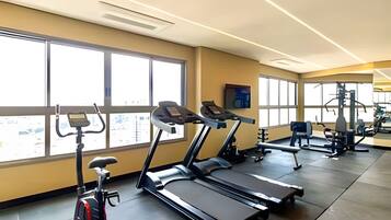 Academia com esteiras, bicicletas ergométricas e máquinas de musculação.