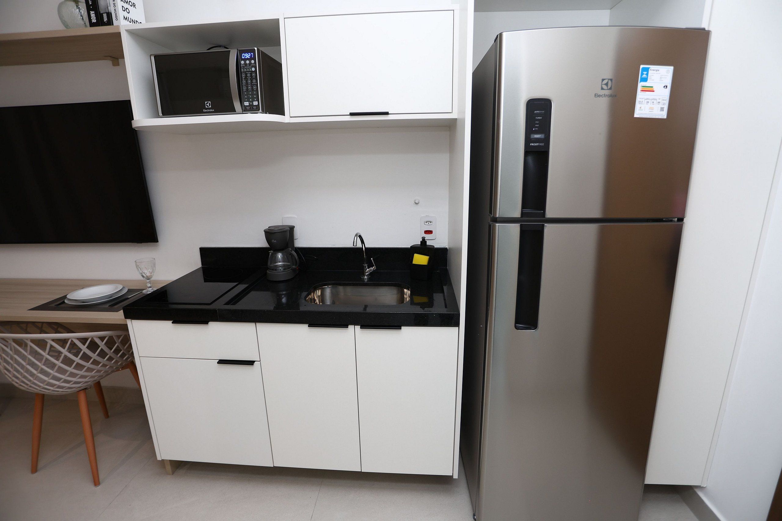 Una kitchenette compacta equipada con microondas, refrigerador, cafetera y pileta.