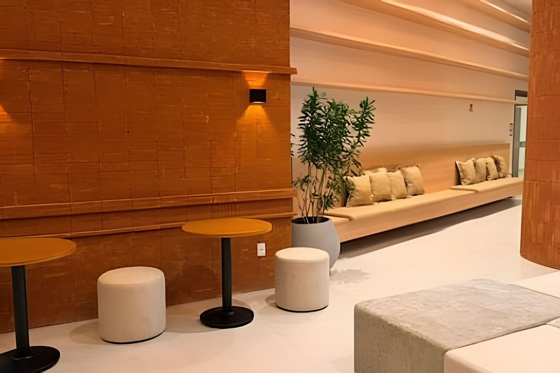 Un intérieur moderne avec un mur en briques, un coin salon avec des coussins et trois tables rondes.