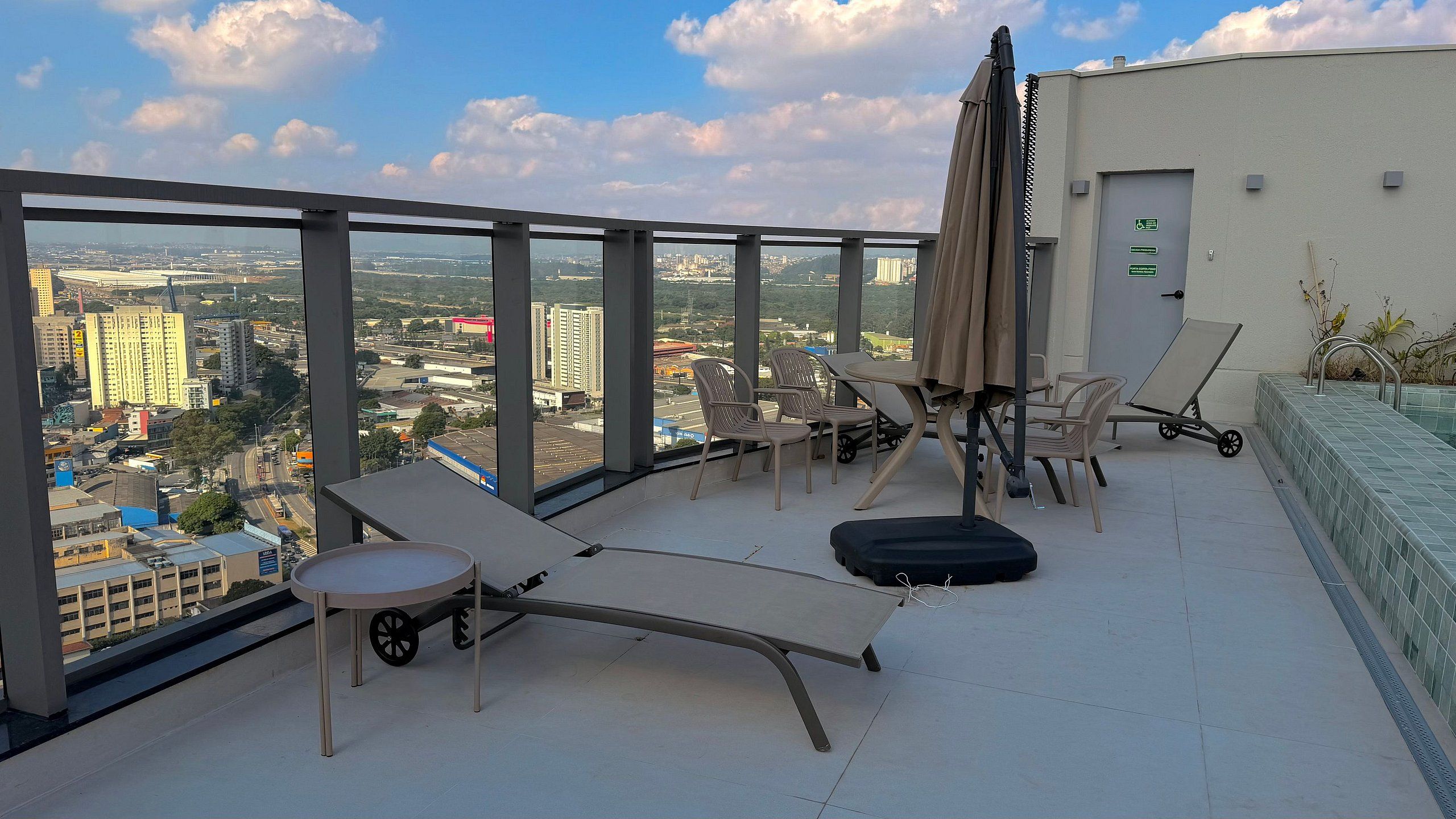 Terraço no telhado com cadeiras de lounge, uma mesa e vista para a paisagem urbana.