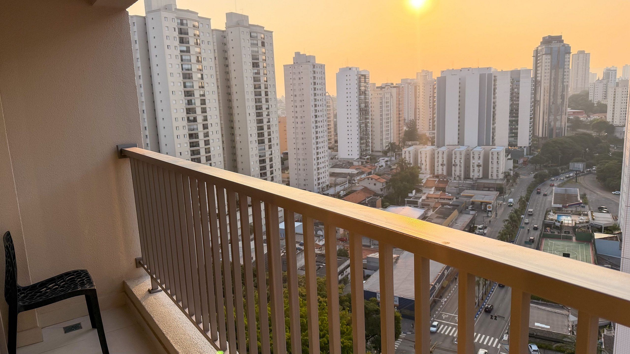 Un balcón con vistas a edificios altos y una calle con vehículos.