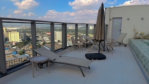 Una terraza en la azotea con sillones de descanso, una mesa y vistas a la ciudad.