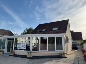 Ein eingeschossiges Gebäude mit flachem Dach, großen Fenstern und einem Schild, das einen Verkauf anzeigt.