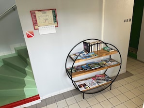 Eine Treppe mit grünen Stufen, ein an der Wand befestigter Evakuierungsplan und ein Bücherregal mit Zeitschriften.