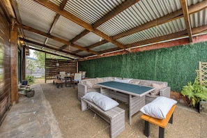Eine Terrasse im Freien mit Tisch und Stühlen, umgeben von einem Holzzaun und einer begrünten Wand.