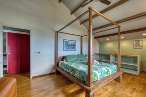 Ein Raum mit einem Himmelsbett, Holzbalken, einer roten Tür und einer grünen Wand.