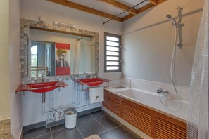 Casa de banho com duas pias, chuveiro e um espelho grande.