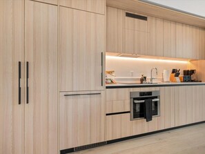 Eine moderne Küche mit Holzschränken, einem eingebauten Ofen und einer Arbeitsplatte mit Kaffeemaschine.