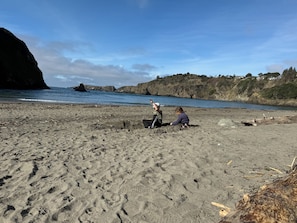 Una playa arenosa con huellas, un acantilado rocoso y un mar tranquilo.