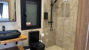 A bathroom with a black sink, a toilet, a shower, and a towel rack.