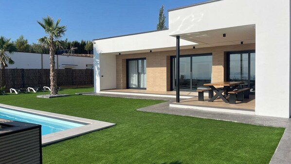 A modern house with a swimming pool, patio furniture, and a covered outdoor seating area.