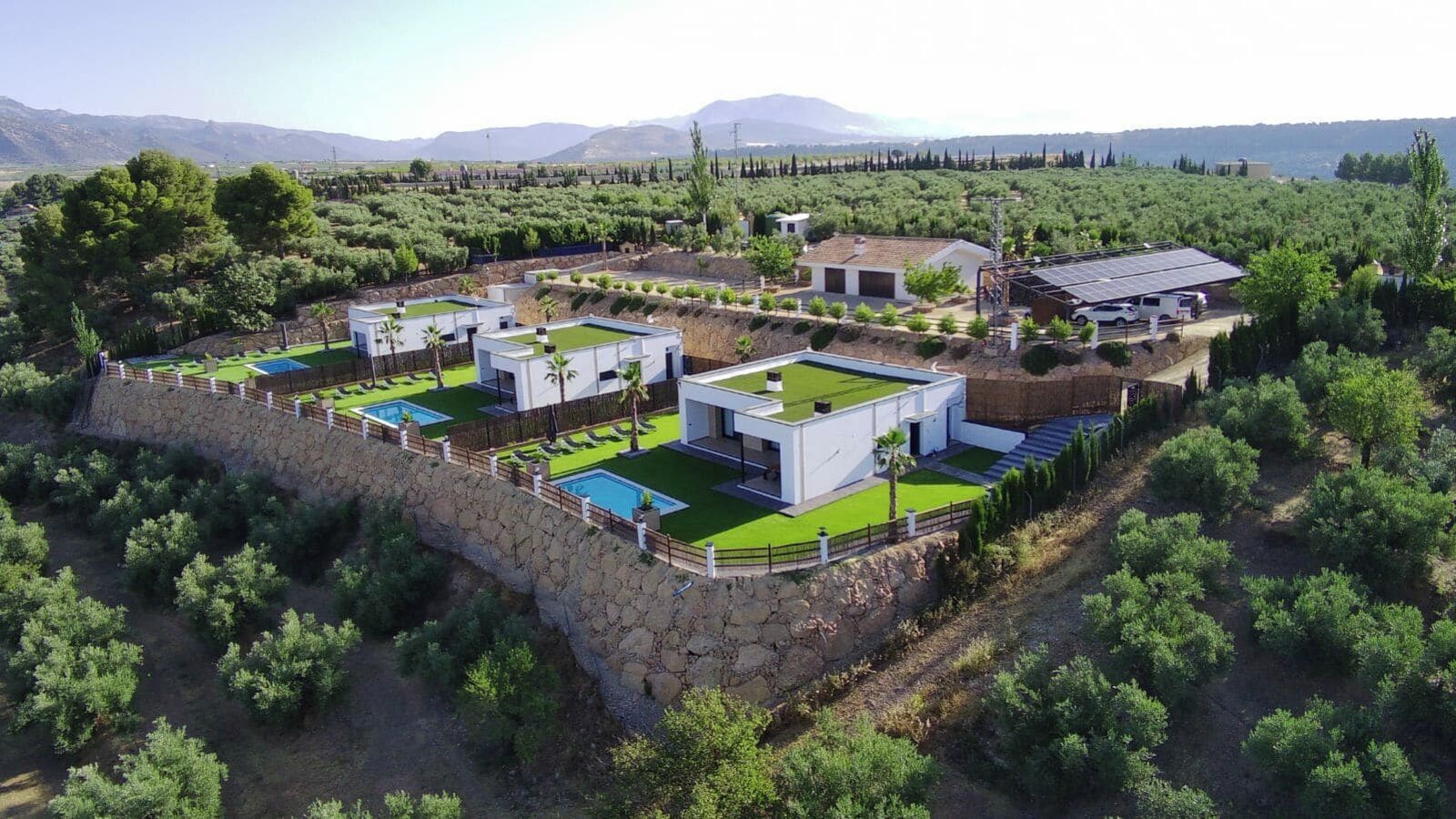 A modern resort with multiple buildings, a swimming pool, and a view of the surrounding landscape.