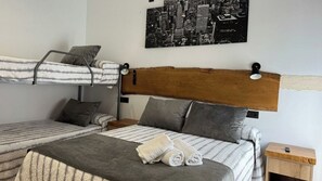 Une chambre avec un lit superposé, une affiche représentant un paysage urbain, une tête de lit en bois et une table de chevet avec une lampe.