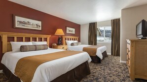 A hotel room with two beds, a TV, a lamp, a dresser, and a window with curtains. - Steamboat Springs Ski Escape with Hot Tubs & Spacious 2BR Deluxe Stay (Steamboat Springs)