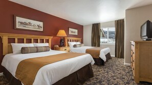 A hotel room with two beds, a TV, a lamp, a dresser, and a window with curtains. - Steamboat Springs Ski Escape with Hot Tubs & Spacious 2BR Deluxe Stay (Steamboat Springs)
