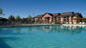 A swimming pool with lounge chairs and a building with multiple balconies in the background. - Steamboat Springs Ski Escape with Hot Tubs & Spacious 2BR Deluxe Stay (Steamboat Springs)