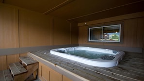 Jacuzzi en una cabana de fusta amb una finestra i una banca de fusta.