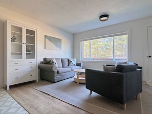 A living room with a sofa, a coffee table, a cabinet, and a window. - Resting Beach Place | Luxurious Beachfront Condo (Neskowin)