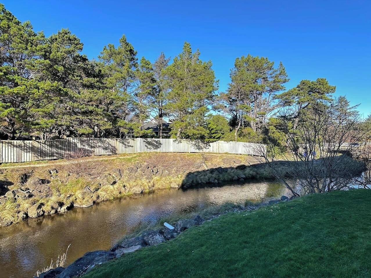 A natural landscape with a stream, grassy areas, and trees.