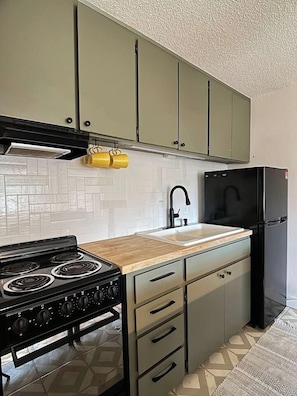 A kitchen with a stove, sink, and refrigerator. - Resting Beach Place | Luxurious Beachfront Condo (Neskowin)
