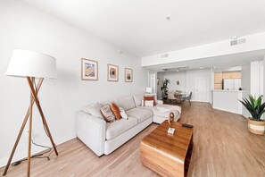 Un saló modern amb un sofà, taula de centre i làmpada de peu. Es veu una cuina al fons.