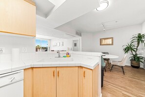 A modern kitchen with a large island, white cabinetry, and a dining area with a table and chairs.