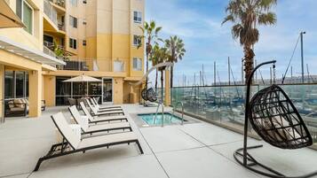 A rooftop pool area with lounge chairs, a small pool, and a view of the marina.