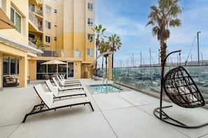 A rooftop pool area with lounge chairs, a small pool, and a view of the marina.