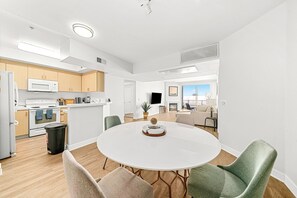 Une cuisine moderne avec des meubles blancs, un four à micro-ondes et un four traditionnel. On y trouve également un coin repas avec une table ronde et des chaises.