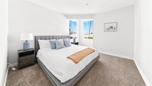 Una camera da letto con un letto grande, un comodino, una lampada, una finestra con vista e un quadro appeso al muro.