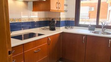 A kitchen with wooden cabinets, a stainless steel sink, and a window providing a view outside.