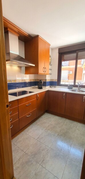 A kitchen with wooden cabinets, a stainless steel sink, and a window providing a view outside.