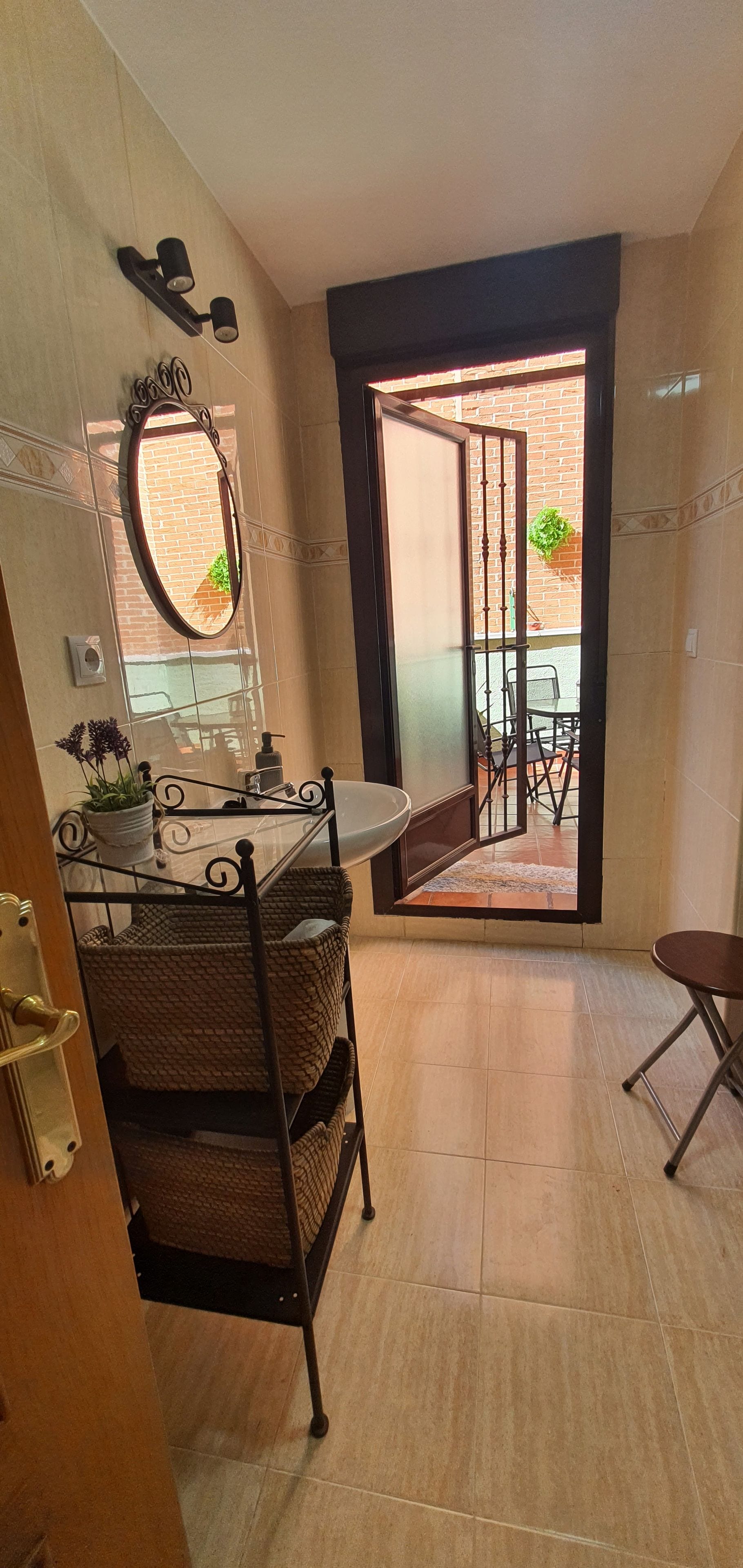 A bathroom with a sink, mirror, and a view of an outdoor patio.