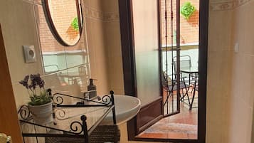 A bathroom with a sink, mirror, and a view of an outdoor patio.