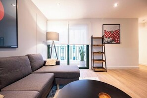 A modern living room with a grey sofa, a black coffee table, and a floor lamp. There is a balcony with a view outside. - Bohemian Barranco Apartments By Geko (Barranco)