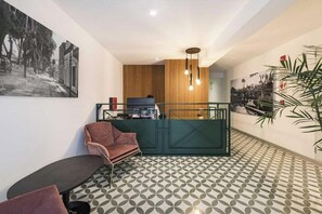 A modern interior with a reception desk, seating area, patterned floor, and wall art. - Bohemian Barranco Apartments By Geko (Barranco)