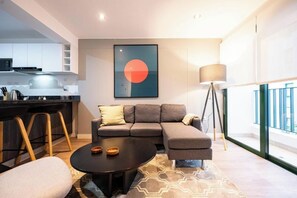 A modern living room with a sectional sofa, a round coffee table, and a large window with a view. - Bohemian Barranco Apartments By Geko (Barranco)