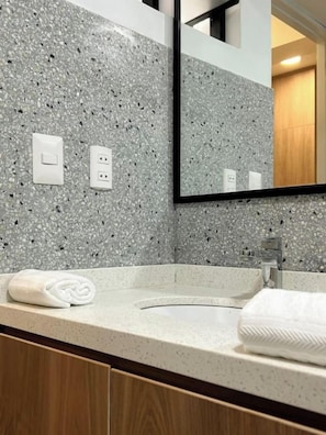 A bathroom with a granite countertop, a sink, a mirror, and a towel. - Miraflores City Diagonal Apartments By Geko (Miraflores)