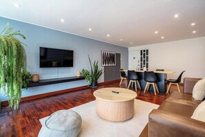A modern living room with a flat-screen TV, a round coffee table, and a sofa. - Contemporary Pardo Miraflores Apartment By Geko (Miraflores)