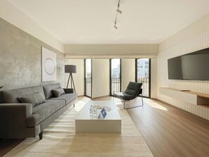 Ein modernes Wohnzimmer mit einer Couch, einem Couchtisch und einem Fernseher.